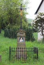 Kovov kek osazen do kamennho podstavce, do nho je osazen obrzek Panny Marie. Kamenn podstavec je obehnn kovovm pltkem